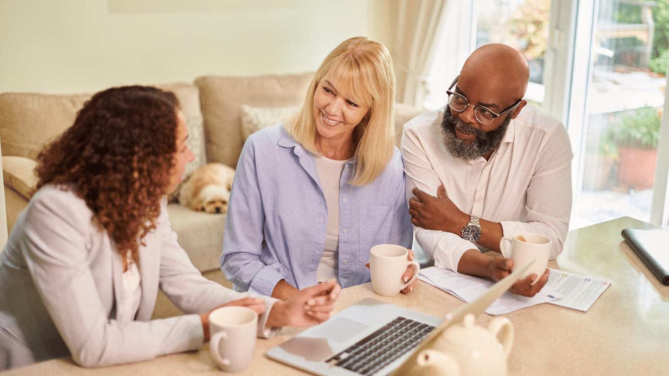 Two women and one man looking at a laptop computer