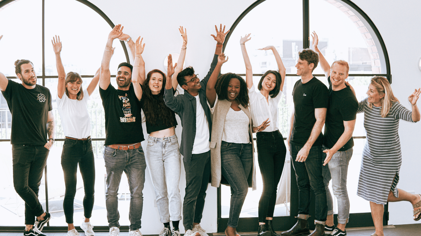 A group of young professional pose for photos in front of windows